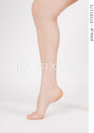 Barefoot and legs isolated on white background. Closeup shot of healthy beautiful female feet. Health and beauty concept. Side view of human foot ream with neutral manicure or pedicure. Sole of foot. 87265173