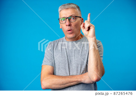 Senior man has a good idea, point finger up on blue background Senior man has a good idea, point finger up on blue background 87265476