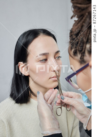 Closeup of a young woman's visage with piercing septum hanging from her nose. Closeup of a young woman's visage with piercing septum hanging from her nose. 87267143