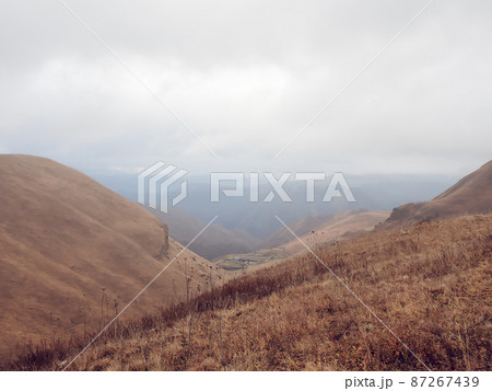 Autumn mountain landscape with dry grass covered with misty haze. Caucasian countryside 87267439