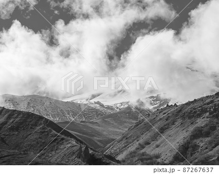 White clouds descended on the majestic Elbrus in the Caucasian mountain valley. Black and white photo White clouds descended on the majestic Elbrus in the Caucasian mountain valley. Black and white photo 87267637