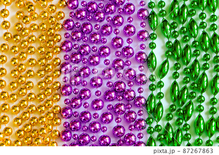 Mardi Gras background. Multi-colored beads close-up. Festive decorations in gold, green and purple colors. Fat Tuesday symbol. Mardi Gras background. Multi-colored beads close-up. Festive decorations in gold, green and purple colors. Fat Tuesday symbol. 87267863