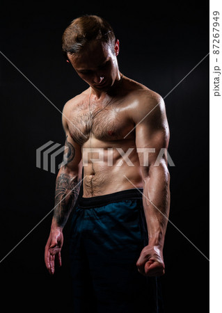 Man on black background keeps dumbbells pumped up in fitness active biceps training exercise lifting dumbbell, healthy pectoral. Lift skin gym fit View from the bottom up good press beautiful muscles 87267949