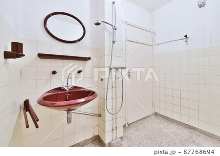 An empty bathroom with a bardic sink and a round mirror 87268694