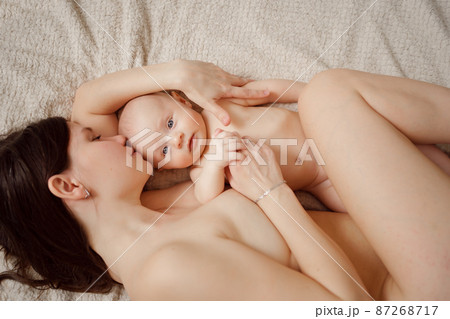 a naked mother and the baby on the bed. maternal and child health.  87268717
