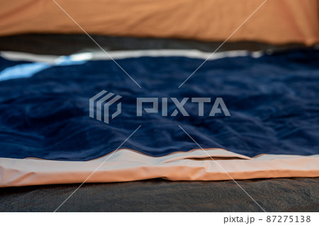 Selective focus of an inflatable air mattress on the floor of a tent being filled up.  87275138