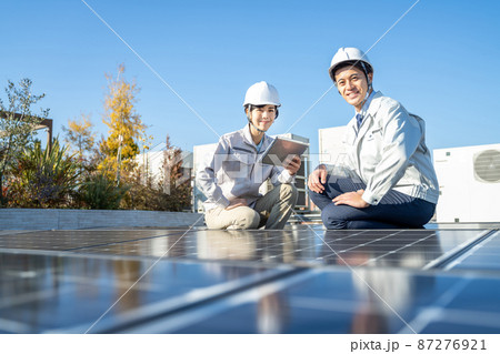 ソーラーパネルをチェックするビジネスマンと女性作業員 87276921