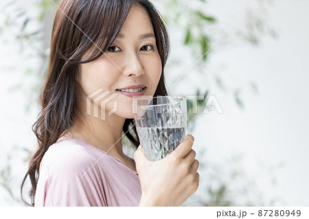 水の入ったグラスを持つ部屋着の女性 87280949