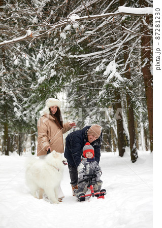 Family of mother, father and son having fun in snowy winter wood with cheerfull pet dog. Family of mother, father and son having fun in snowy winter wood with cheerfull pet dog. 87281230