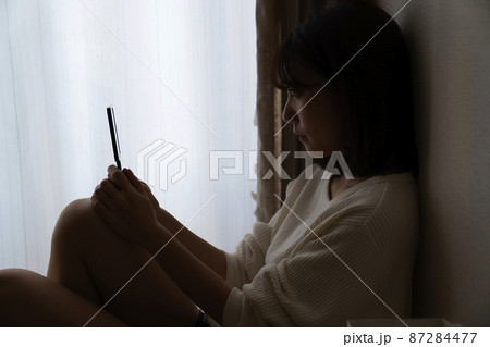 暗い部屋で座る女性 暗い部屋で座る女性 87284477