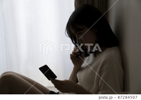 暗い部屋で座る女性 87284507