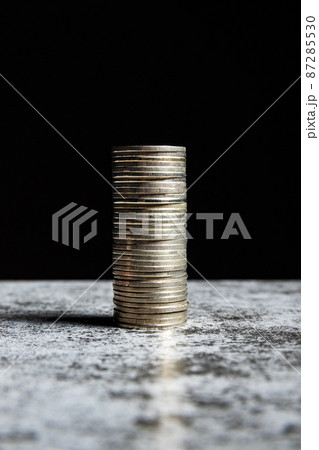 Stack of coins on grey table and black background Stack of coins on grey table and black background 87285530