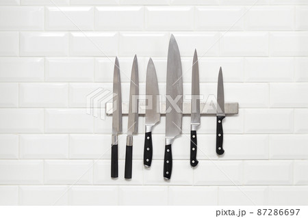 Six Japanese knifes hanging on white wall tile Six Japanese knifes hanging on white wall tile 87286697