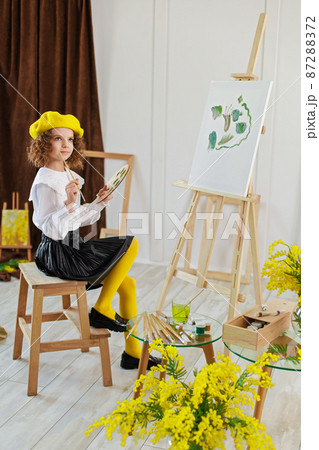 Little girl painting a picture in a studio or art school. Creative pensive painter child paints a colorful picture on canvas in workshop. Talented kids 87288372