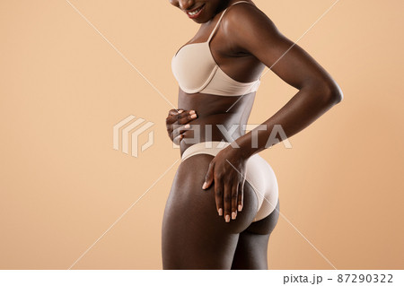 Dark skinned lady touching smooth skin on her buttocks 87290322