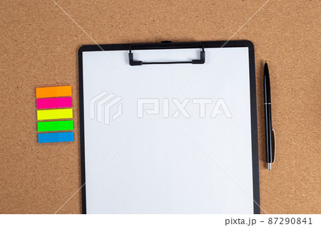 A notepad with a blank sheet of paper and a pen next to it on the table. A notepad with a blank sheet of paper and a pen next to it on the table. 87290841