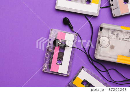 Cassette player with earphones and cassette tapes on purple background. 87292243