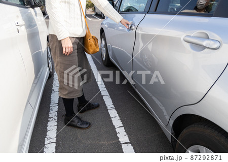 狭い駐車場で車から降りる女性 87292871