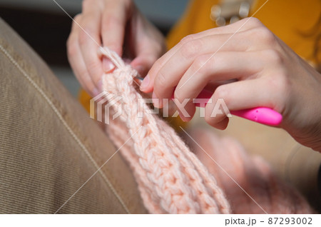 The hands of a young caucasian woman are knitting a woolen product indoors. The concept of hobby and the creation of clothes from wool The hands of a young caucasian woman are knitting a woolen product indoors. The concept of hobby and the creation of clothes from wool 87293002