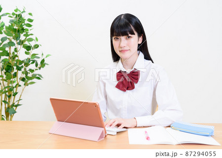 タブレット端末にキーボードで入力しながら勉強する女子高校生　動画視聴　オンライン授業　 87294055