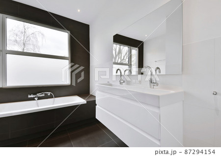 A minimalist bathroom with a bathtub and a window above it A minimalist bathroom with a bathtub and a window above it 87294154