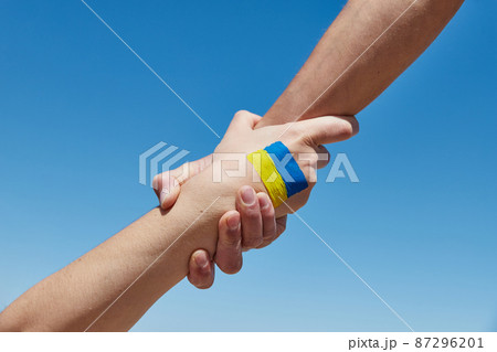 Lend a hand help painted in ukrainian flag colors against blue sky. Stand with Ukraine 87296201
