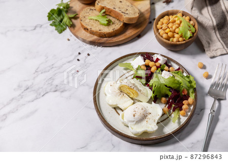 Easter breakfast or brunch. Poached egg and beet salad with spinach, cheese feta, chickpeas on a marble tabletop. Copy space. Easter breakfast or brunch. Poached egg and beet salad with spinach, cheese feta, chickpeas on a marble tabletop. Copy space. 87296843