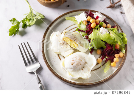 Easter breakfast or brunch. Poached egg and beet salad with spinach, cheese feta, chickpeas on a marble tabletop. 87296845