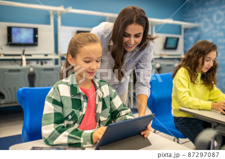 Woman looking into tablet of happy girl Woman looking into tablet of happy girl 87297087