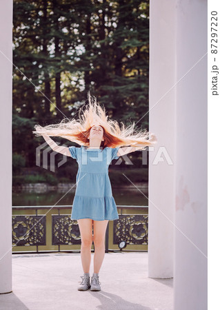 A girl in a short dress waved her long red hair while standing in the architecture of the park. Photo in contour light 87297220