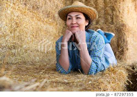 Female farmer posing in the barn against backdrop of hay bales 87297355