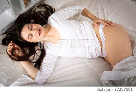 Young woman in white sleepwear sleeping in bed in home 87297591