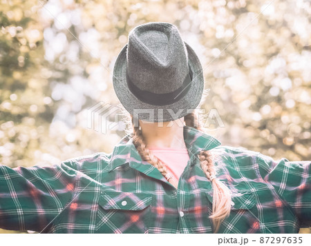 Portrait of a lady with a hat put on her face in a plaid shirt standing outdoors. Posterization Portrait of a lady with a hat put on her face in a plaid shirt standing outdoors. Posterization 87297635