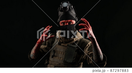photo of a man in a military uniform and balaclava with a bloody face and hands up to the elbow in blood on a black background 87297883