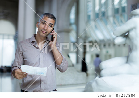 Adult male is visiting at the exposition with brochure and talking by phone Adult male is visiting at the exposition with brochure and talking by phone 87297884