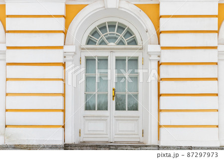 Old white wooden door in yellow wall, background texture 87297973