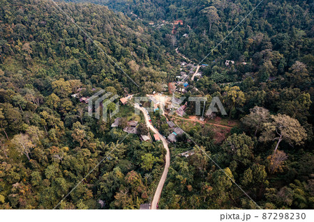Aerial view of local rural village with gravel road through in the valley on faraway at countryside among the tropical rainforest 87298230