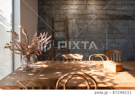 Interior of living room with wooden table, chair, dry leaf in glass wave, tissue box and wooden stair on concrete wall 87298231