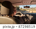 unrecognizable blonde woman driving a car on the road 87298519