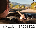 unrecognizable blonde woman driving a car on the road 87298522