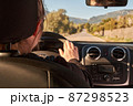 unrecognizable blonde woman driving a car on the road 87298523