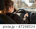 unrecognizable blonde woman driving a car on the road 87298524