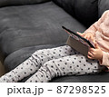 unrecognizable girl sitting on the sofa using a tablet 87298525