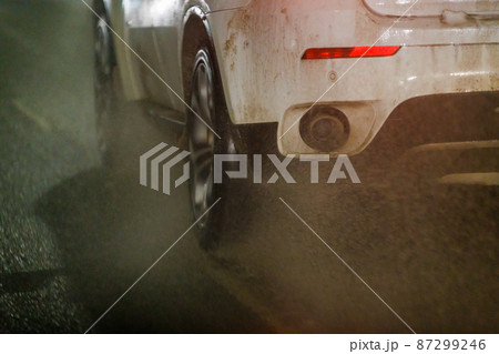 dirty water ejecting out from white car driving on night winter road 87299246