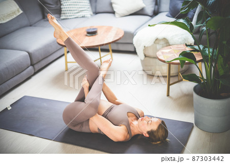 Young beautiful pregnant woman training pilates at home in her living room. Healthy lifestyle and active pregnancy and motherhood concept. 87303442