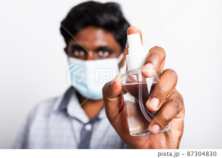 black man wearing protective face mask fear in eye holding show sanitizer spray black man wearing protective face mask fear in eye holding show sanitizer spray 87304830