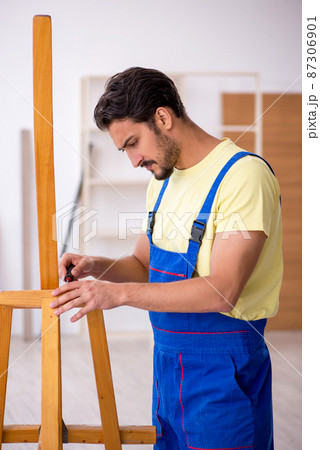 Young male repairman repairing easel at home 87306901