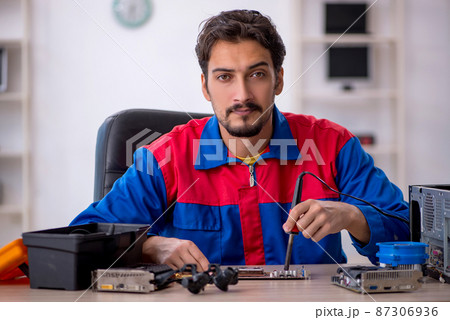 Young male repairman repairing computer Young male repairman repairing computer 87306936
