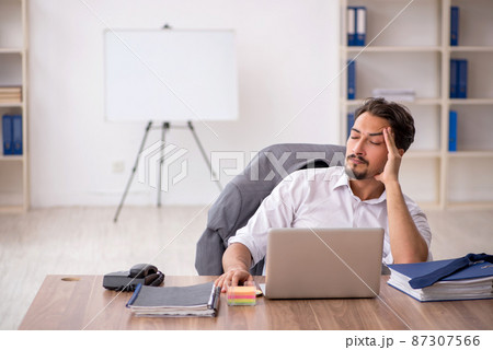 Young male employee sitting in the office Young male employee sitting in the office 87307566