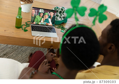African american couple having st patrick's day video call with a group of friends on laptop at home African american couple having st patrick's day video call with a group of friends on laptop at home 87309103